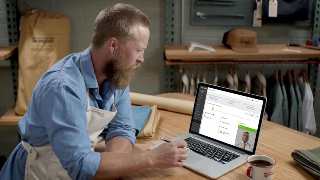 一个家伙在笔记本电脑上使用QuickBooks Live Bookkeeper应用程序。